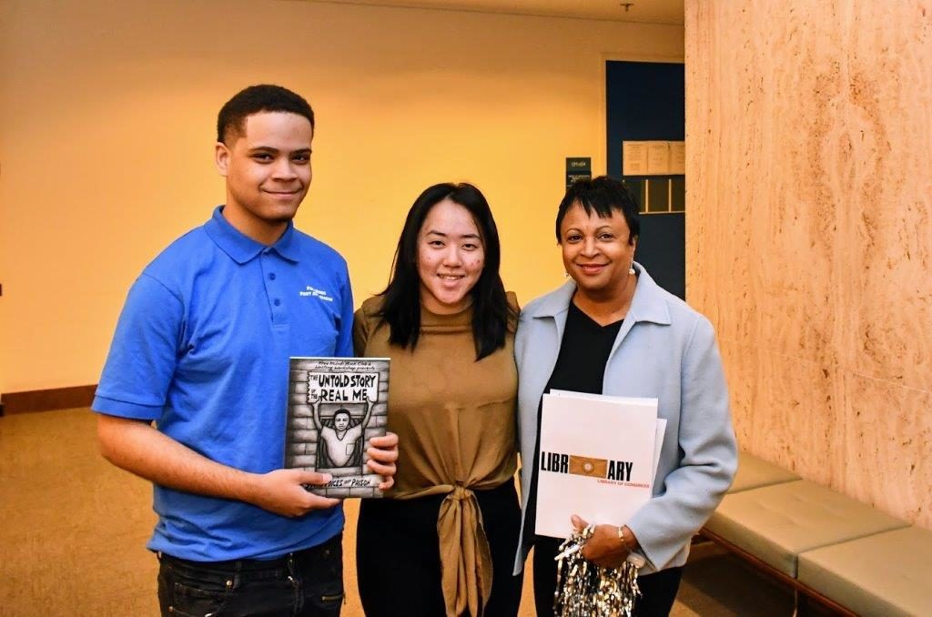 Three people stand in a row holding a book called The Untold Story of the Real Me