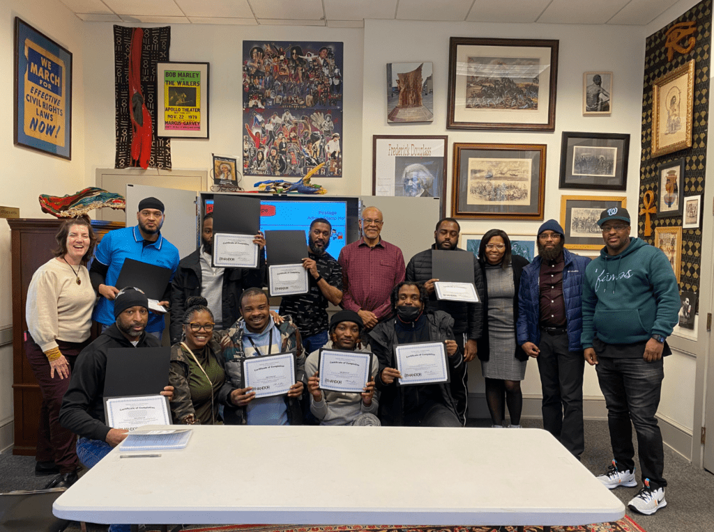 A group of men stand together holding up certificates