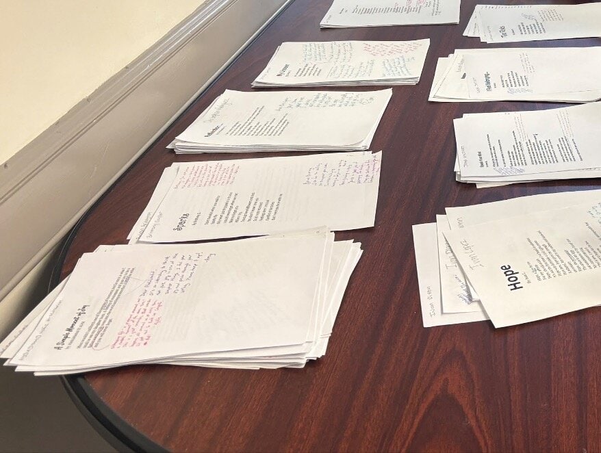 Stacks of poems with brightly colored comments written on them