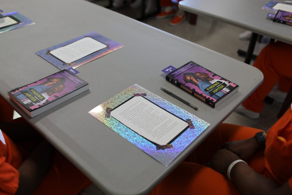 A table in the library at the DC Jail with copies of the book Finding Jupiter and materials for a blackout poetry workshop for the Women's Book Club.