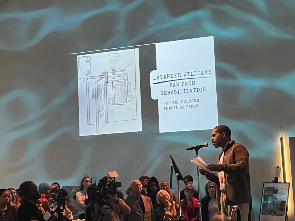 A man standing at a microphone reciting a poem before a crowd.