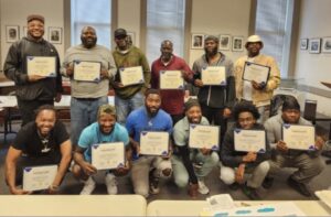 A group photo of Free Minds members holding certificates from their apprenticeship graduation.